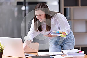 Businesswomen standing working with a laptop and holding documents in the office