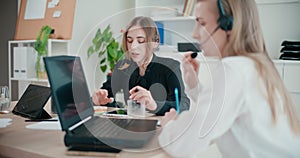 Businesswomen talking through headsets at desk