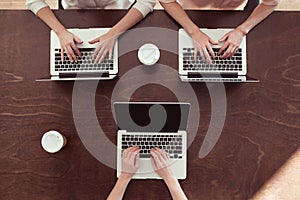 Businesswomen typing on laptops at table