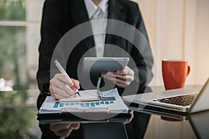 Businesswomen use tablet and laptop computer and take notes in the notebook at the office desk in the morning