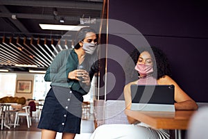 Businesswomen Wearing Masks Having Socially Distanced Meeting In Office