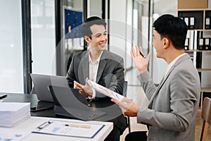 Businesswomen work and discuss their business plans. A Human employee explains and shows her colleague the results paper