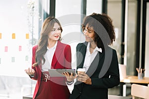 Businesswomen work and discuss their business plans. A Human employee explains and shows her colleague the results paper in modern