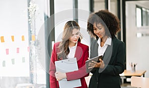 Businesswomen work and discuss their business plans. A Human employee explains and shows her colleague the results paper in modern