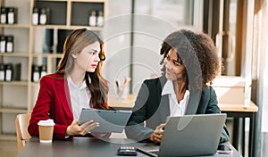 Businesswomen work and discuss their business plans. A Human employee explains and shows her colleague the results paper in modern