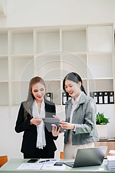 Businesswomen work and discuss their business plans. A Human employee explains and shows her colleague the results paper in office