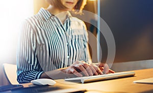 Businesswomen working at office with monitor computer at night, young hipster manager typing on keyboard, female hands texting mes