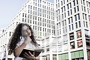 Businnes woman talking on the mobile phone with client and checks the schedule in her notebook