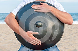 Busker hold the Hang or handpan with sea on photo