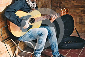 A busker playing Spanish acoustic guitar with a small amplifier in the street