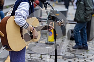 Busker. Singer guitarist with acoustic guitar. Selective focus on foreground