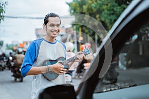 busker use musical instruments and sing in front of the car on the traffic lights crossroad