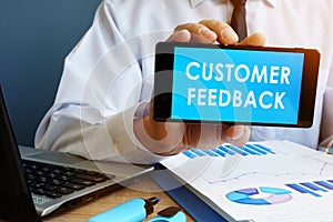 Busnessman holding phone with Customer Feedback.
