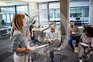 Bussines woman lecturing her multiethnic colleagues. Having a speach while holding a microphone