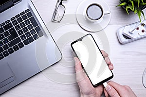 Bussines wooden office desk workplace with blank cellphone, various supplies. It puts the phone on charge .Mock up. Laptop ,hand