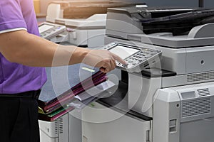 Bussinessman using copier machine to copy heap of paperwork in office
