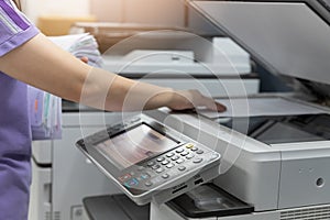 Bussinesswoman using copier machine to copy heap of paperwork in office