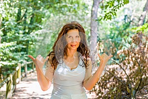 Busty classy mature woman doing welcome shaka sign