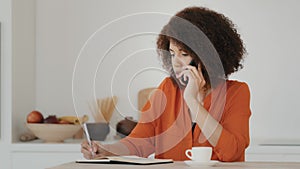 Busy African American business woman curly hair girl student worker housewife working paperwork talking on phone at home