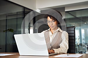 Busy African American business woman using laptop computer working in office.