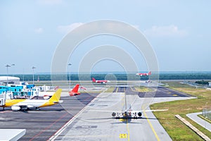 A busy airport tarmac runway with various commercial aircraft planes parked near the terminals