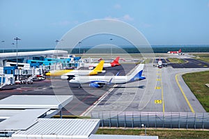 A busy airport tarmac runway with various commercial aircraft planes parked near the terminals