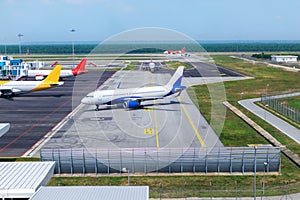 A busy airport tarmac runway with various commercial aircraft planes parked near the terminals