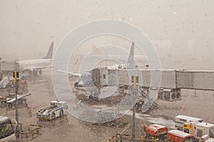 Busy airport view with airplanes and service vehicles at snowy winter day