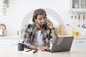 Busy arab man freelancer talking on phone and using laptop