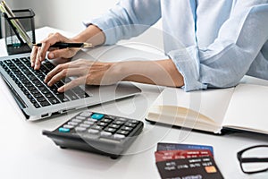 Busy Asian businesswoman working on laptop computer at office. Woman checking account balance and calculating credit card expenses