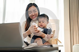 A busy Asian working woman mom is focusing on her work and taking care of her cute little son