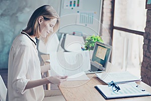 Busy assistant is sitting at her workplace and checking document
