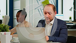 Busy business man using laptop typing sitting at conference table in broadroom