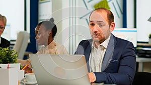 Busy business man using laptop typing sitting at conference table in broadroom