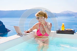 Busy business woman working while on vacation in pool