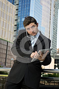 Busy businessman holding digital tablet and mobile phone overworked outdoors