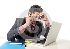 Busy businessman working in stress on computer laptop talking on mobile phone