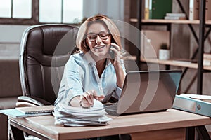 Busy businesswoman speaking by the phone with her partner