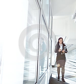 Busy businesswoman walking to her office holding files and drinking coffee. One female lawyer carrying documents and a