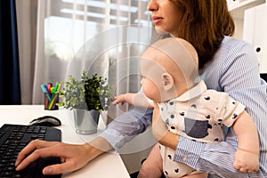 Busy businesswomen working at a office with a baby on her hands.