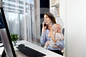 Busy businesswomen working at a office with a baby on her hands.