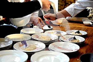 Busy chefs in a restaurant arranging and decorating glamorous delicious food on a wooden table for a dinner party - cuisine