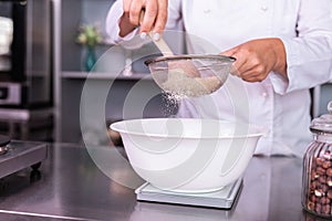 Busy confectioner bolting flour while cooking sweet pie photo