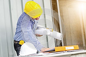 Busy construction engineer talking on phone while carrying blueprints with checking the building progress