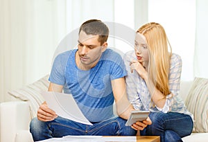 Busy couple with papers and calculator at home