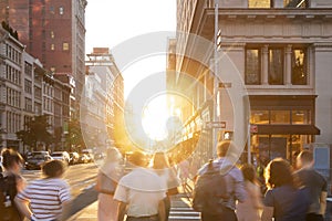 Busy crowds of people walking down the sidewalk on 23rd Street in New York City with sunlight background photo