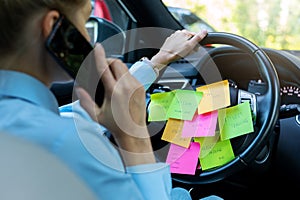 Busy day schedule concept - woman driving car with to do list notes on the wheel