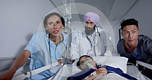 Busy diverse doctor and surgeons talking and walking with patient on hospital bed in slow motion