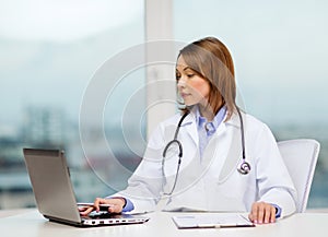 Busy doctor with laptop computer and clipboard