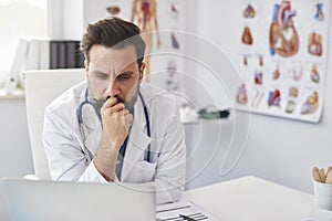 Busy doctor working with laptop in doctorÃ¢â¬â¢s office photo